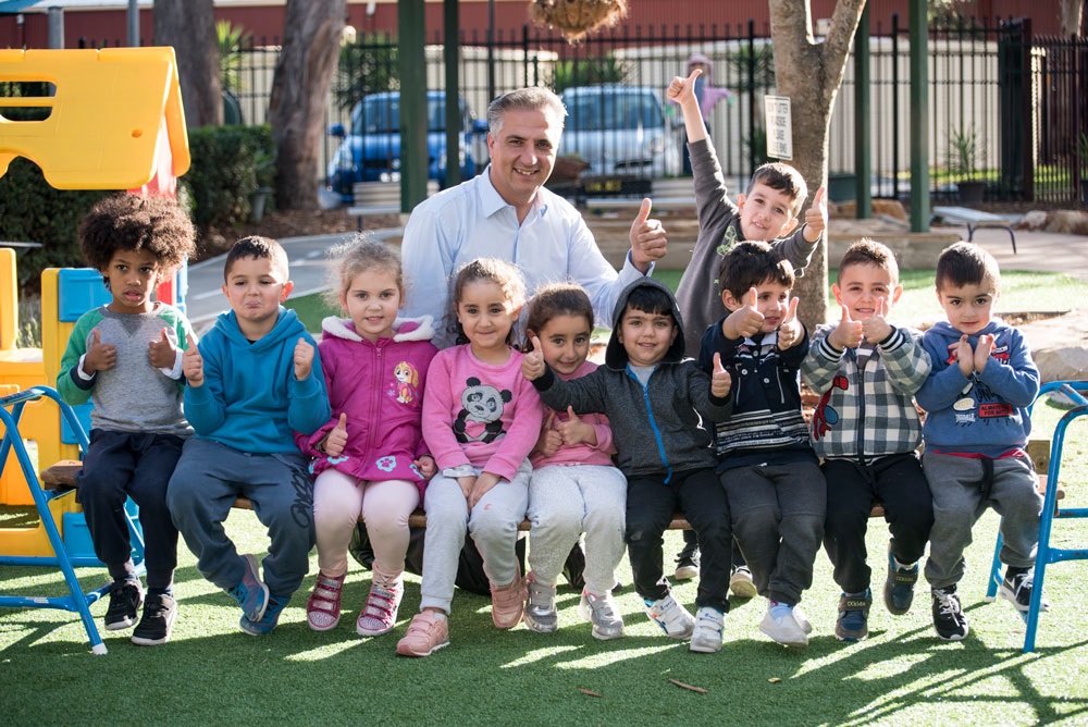 Mayor Frank Carbone smiling and posing with group of young children, holding their thumbs up 