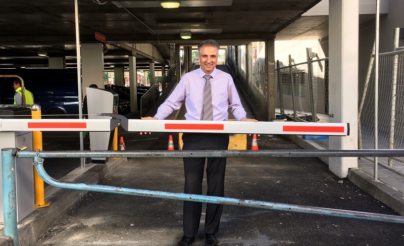 Mayor Frank Carbone smiling and posing with boom gates at Dutton Lane car park in Cabramatta