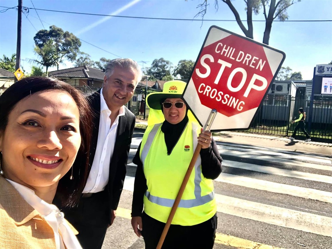 Mayor Frank Carbone and Councillor Dai Le smiling and posing with lollipop woman holding a sign saying 