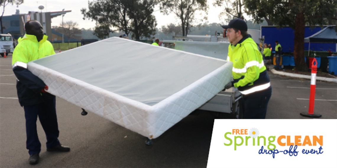 Two men wearing high visibility vests, carrying an old and disposed mattress for the Spring Clean Drop Off Event at Fairfield Showground 