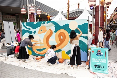 3 ladies painting a dragon in a Live Mural Painting