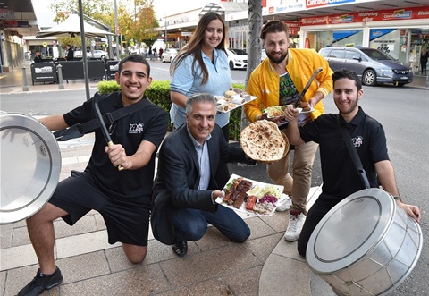 Mayor Frank Carbone smiling and posing with people holding plates of food 