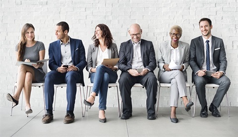 Diverse group of six business people sitting together in a row and smiling