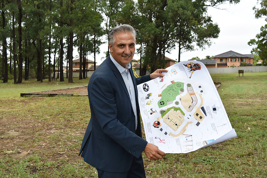 Mayor Frank Carbone smiling and holding plans for Deerbush park on a large sheet of paper 