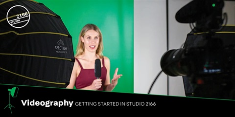 A woman holding a microphone stands with a camera and a green screen, preparing for a creative project or filming session.