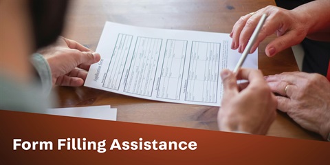 A hand filling a form next to another person.