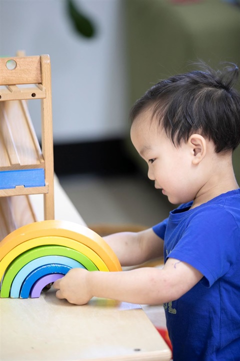 Young boy playing with rainbow toy
